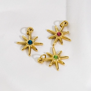 Gold starburst pendants with blue pink and green crystals on white silk background