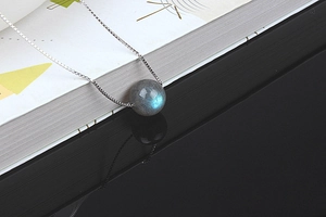 Macro shot of natural labradorite pendant on silver chain with blue light reflection