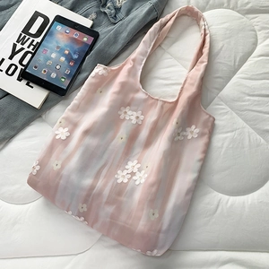 Détail de la broderie florale sur un sac cabas en toile rose sur un lit blanc