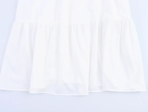 Dettaglio dell'orlo plissettato di un abito bianco in chiffon con trama fluida e morbida
