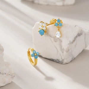 Detailed macro of gold S925 silver earrings with turquoise stones and sparkling zircons