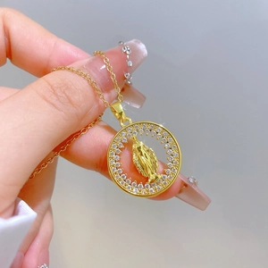 Detail of gold pendant necklace with Virgin Mary motif and sparkling zircon halo