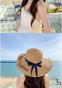 Detail of wide brim straw hat with Hello Sunshine embroidery and black bow ribbon