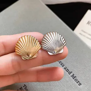 Polished shell-shaped metal ear cuffs in gold and silver finish with radial texture
