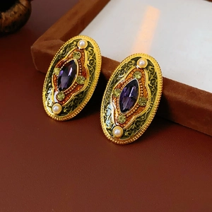 Detail of vintage gold earrings with purple stones, green crystals and pearls