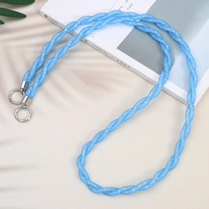 Blue braided crossbody phone lanyard strap with metal hooks on a minimalist magazine