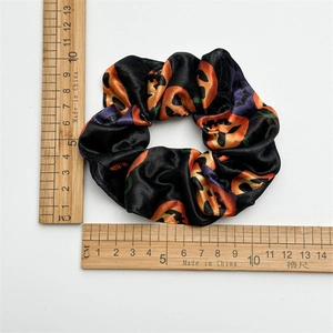 Detail view of Halloween satin scrunchie with orange pumpkin patterns and size reference