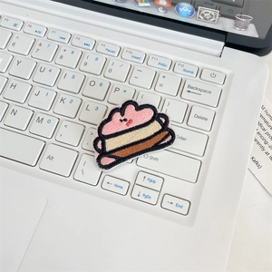 Macro shot of cute cartoon plush embroidery patch on a modern laptop keyboard