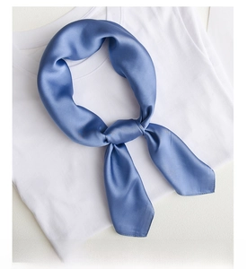 Detail of blue silk neckerchief tied elegantly on a white shirt with satin luster