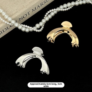 Detail view of gold and silver metal hair claws measuring 6cm x 3cm on elegant black backdrop