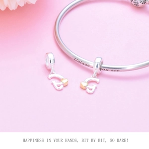 Macro detail of S925 sterling silver charms with gold hearts and engraved bracelet