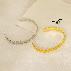 Close-up of heart-shaped hollow textured open bangles in gold and silver finishes
