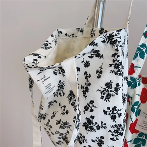 Close-up of vintage floral cotton tote bag featuring black flower patterns and woven label