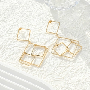 Detail of geometric gold hollowed squares interlocking on elegant French tassel earrings