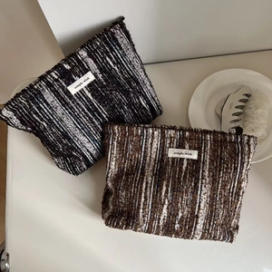 Detail of tweed makeup bags with woven texture, simple wish label and zipper closure