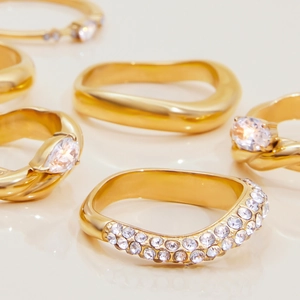 Detailed close-up of gold stainless steel rings featuring zircon pavé and wave textures