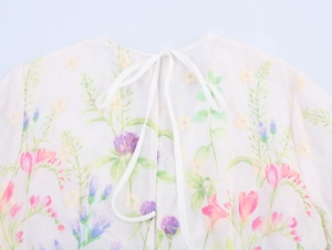 Detail of the back neckline with a white bow tie and floral print on airy chiffon fabric