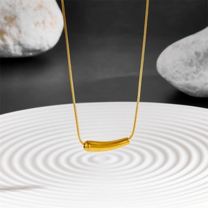 Gros plan du collier pendentif aubergine dorée sur un plateau blanc texturé élégant