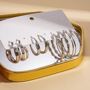 Detail view of silver geometric hoop earrings set in varied textures on a golden tray