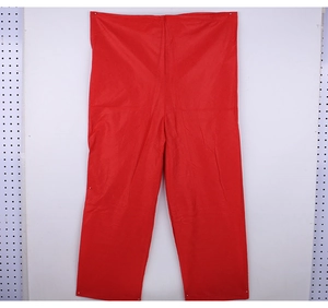 Detailed view of red non-woven Christmas trousers laid flat on white studio background