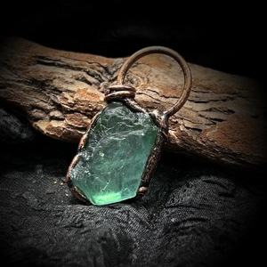 Vista macro del ciondolo in fluorite verde grezza avvolto in filo di bronzo retrò