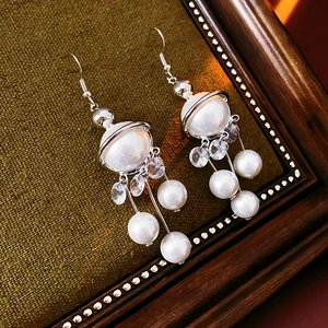 Detailed shot of pearl drop earrings with sparkling zircon tassels on green velvet