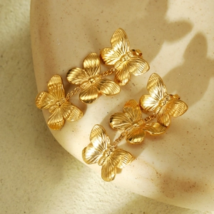 Elegant gold butterfly tassel earrings in polished titanium steel on beige tray