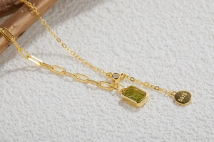Macro shot of S925 silver necklace with green gemstone pendant and paperclip chain