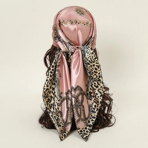 Detail of silk-satin scarf with leopard print and gold chain patterns on a mannequin head