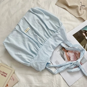 Detailed close-up of light blue pleated canvas tote bag with woven side brand label