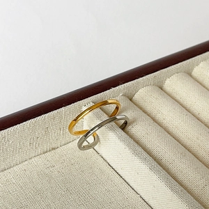 Polished gold and silver minimalist thin band rings displayed in a beige jewelry box