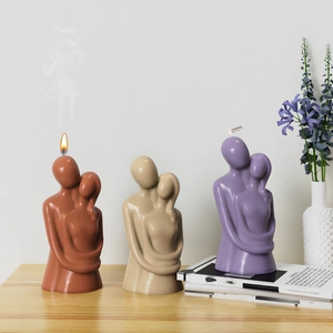 Macro shot of couple embrace resin candles in warm colors on a wooden table with flowers