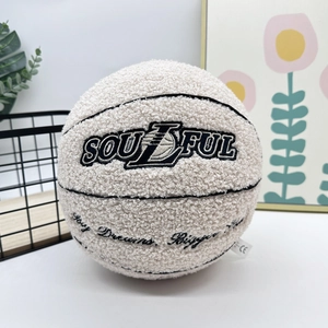 Macro shot of soulful embroidery on a cream plush basketball pillow in a home setting