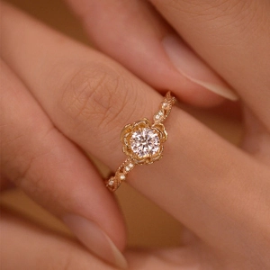 Close-up of rose gold flower ring with sparkling zircon and twisted band worn on finger
