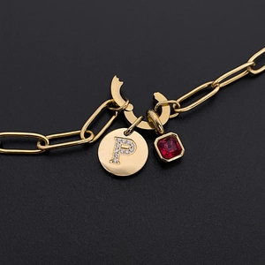 Dettaglio macro di una collana in acciaio al titanio dorato con ciondolo a lettera P