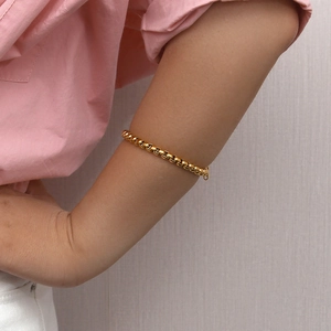 Detailed view of an 18K gold plated stainless steel snake chain bracelet on a wrist