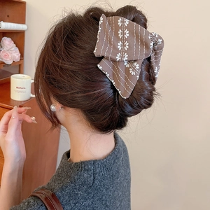 Detailansicht der braunen Stoff-Haarschleife mit floralem Muster und Streifen im Haar
