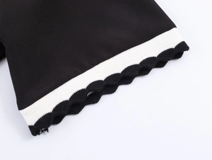 Detail of contrast wave hem cuffs on a black knit polo shirt with sharp texture