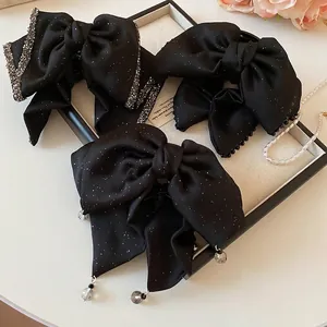 Elegant black satin bow hair clips with rhinestones and beads on a jewelry tray