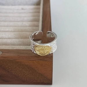 Vintage 925 sterling silver open ring with golden oval saint relief on a wooden box