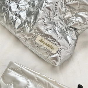 Close-up of quilted silver PU fabric with stitched Sozakka label on the clutch bag