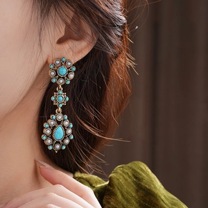 Close-up of vintage bronze flower earrings with turquoise and pearls on model