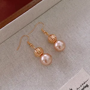 Vintage gold spherical drop earrings with light pink pearls on a textured background