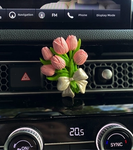 Close-up of pink tulip car diffuser clip with a white bow on the air vent