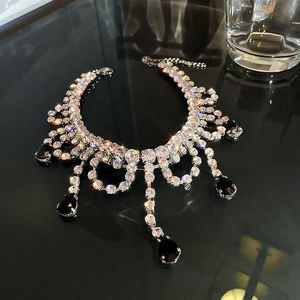 Détail de collier de luxe avec gemmes noires en goutte et cristaux pavés sur miroir