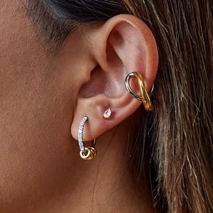 Detail of two-tone gold and silver earrings with small diamond hoop accents on model