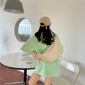 Borsa a tracolla in nylon beige indossata all'esterno con outfit casual e cappello