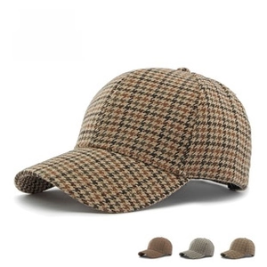 Detail of three houndstooth baseball caps in light gray, dark brown, and camel shades
