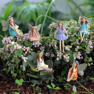 Macro detail of six resin flower fairy figurines nestled in succulent garden plants