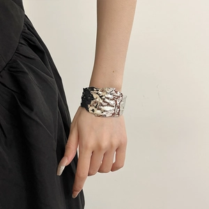 Macro detail of silver irregular crumpled texture on metallic C-shaped open bangle